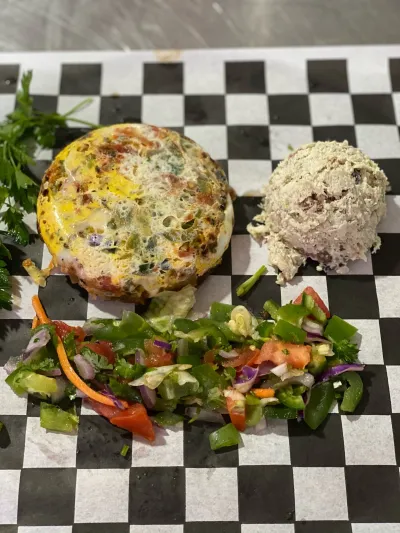 Open face egg bagel with a scoop of salad and Israeli salad